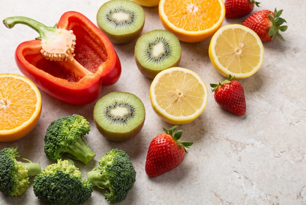 Pimiento rojo, kiwis, naranjas, limones, fresas y brócoli partidos sobre una superficie clara